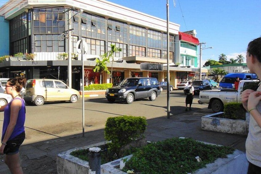 A street with cars, a building with a sign that reads 'JACK'S,' and a person walking. 3