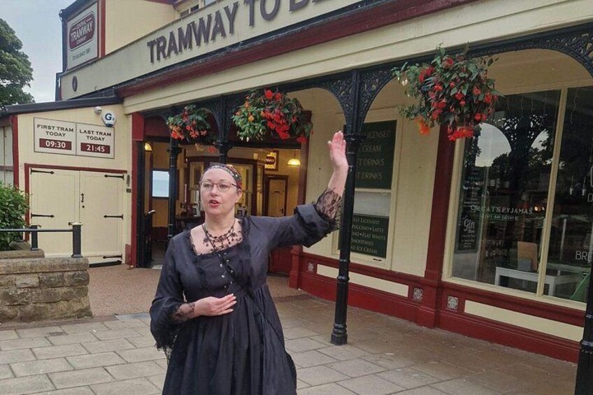 A person in historical costume standing in front of a building with a sign that reads 'TRAMWAY TO BIRMINGHAM.' 5