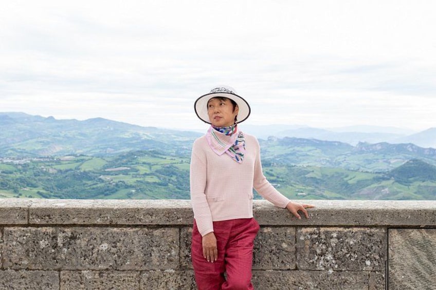 A person standing on a stone wall overlooking a valley with rolling hills. 3