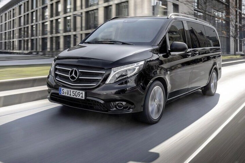 A black Mercedes-Benz S-Class SUV driving on a road with a modern building in the background. 2