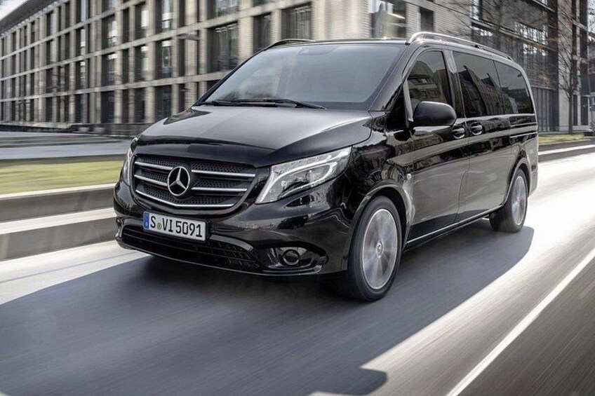 Un SUV Mercedes-Benz noir roule sur une route, avec un bâtiment moderne en arrière-plan. 2