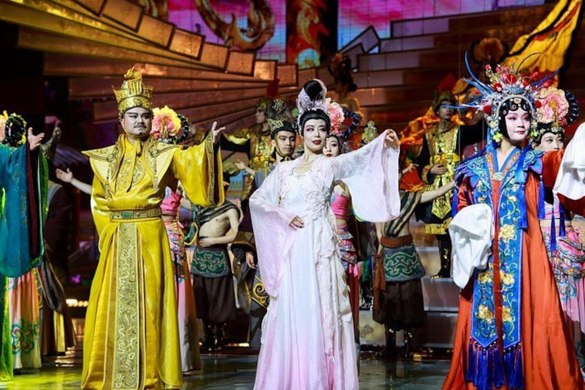 A group of people in traditional costumes on a stage with a backdrop of a building. 5