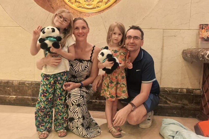 Een gezin met panda knuffels, een patroonwand en een bakstenen muur. 3