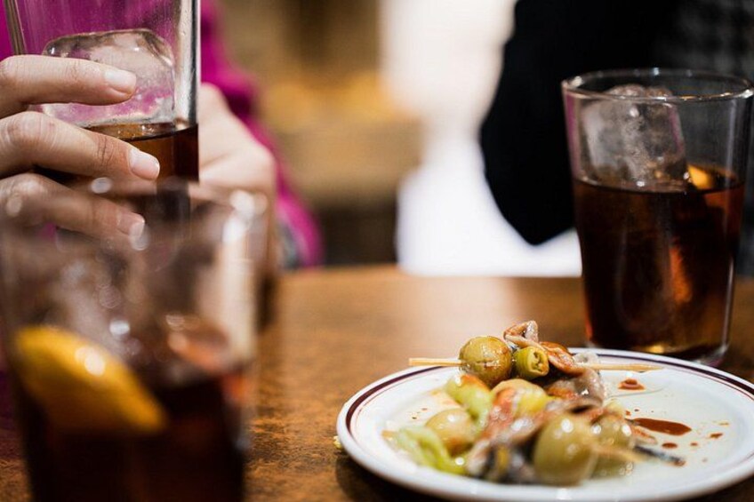 Une personne tenant un verre de thé glacé, une assiette de nourriture avec des olives et un citron, et un autre verre de thé glacé sur une table. 3
