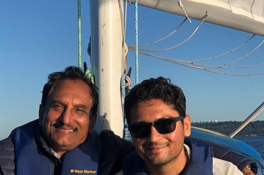 Twee personen op een boot, met een heldere lucht en water op de achtergrond. 5