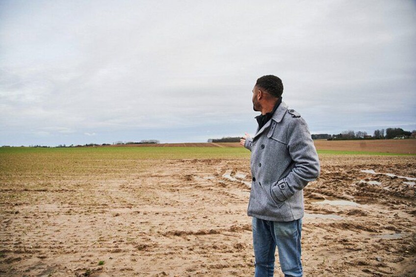 A person standing in a muddy field with a cloudy sky. 3