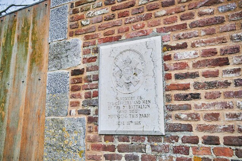 A brick wall with a memorial plaque. 5