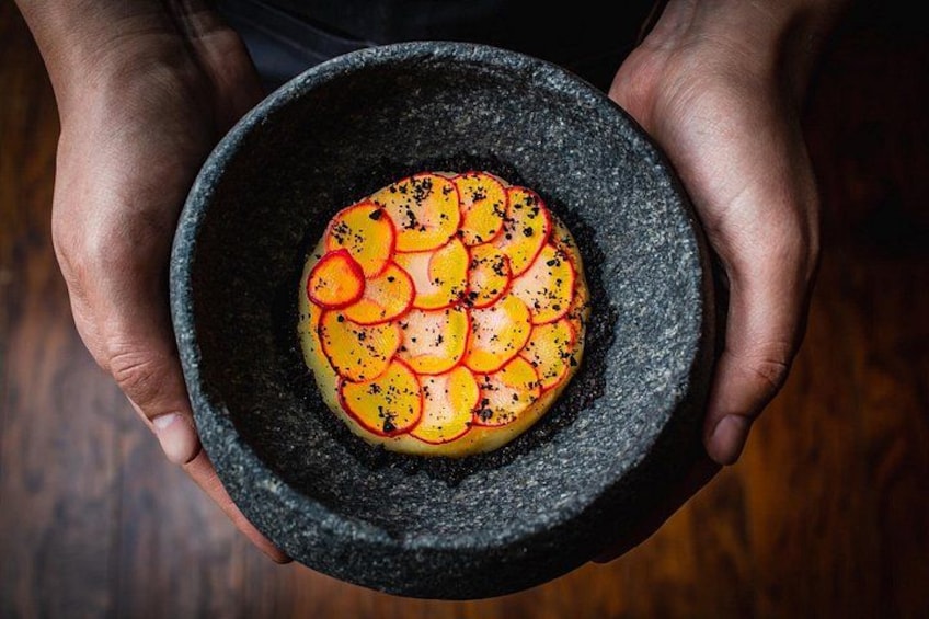 A person holding a bowl with a dish of sliced vegetables. 1