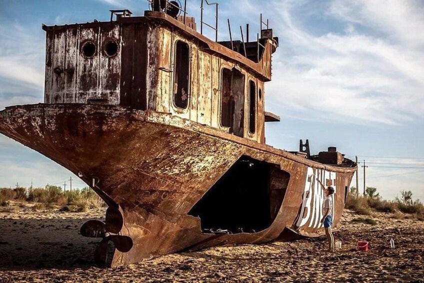 A rusted shipwreck on a sandy beach with a clear sky. 3