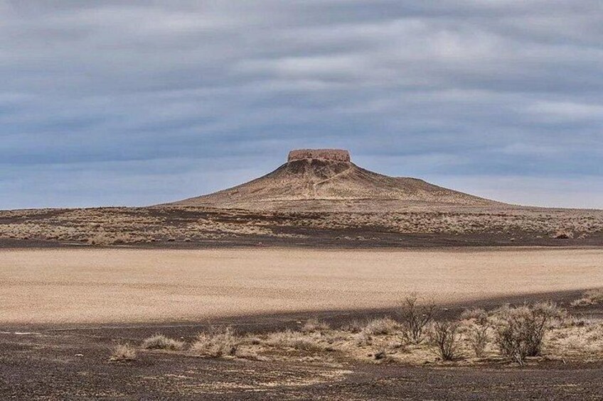 A barren landscape with a prominent hill and a flat plain in the foreground. 4