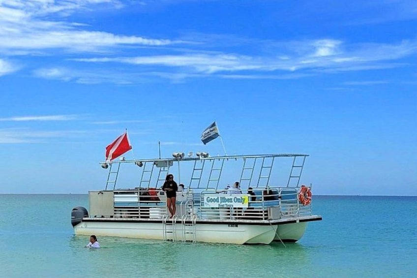 A boat with a flag, a person standing on the deck, and calm water. 3