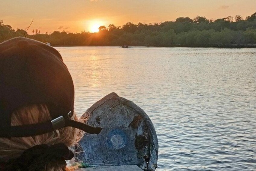 Ein Sonnenuntergang über ruhigem Wasser mit einer teilweise im Wasser befindlichen Holzkonstruktion. 1