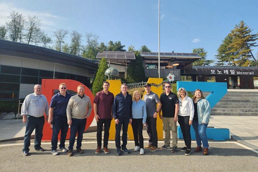 A group of people standing in front of a building with a large, colorful sculpture. 3