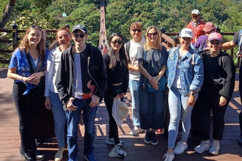 A group of people standing on a wooden deck with a forested background. 2