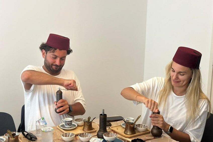Twee personen zitten aan een tafel met een traditionele Midden-Oosterse theeset, inclusief theepotten en kopjes. 2