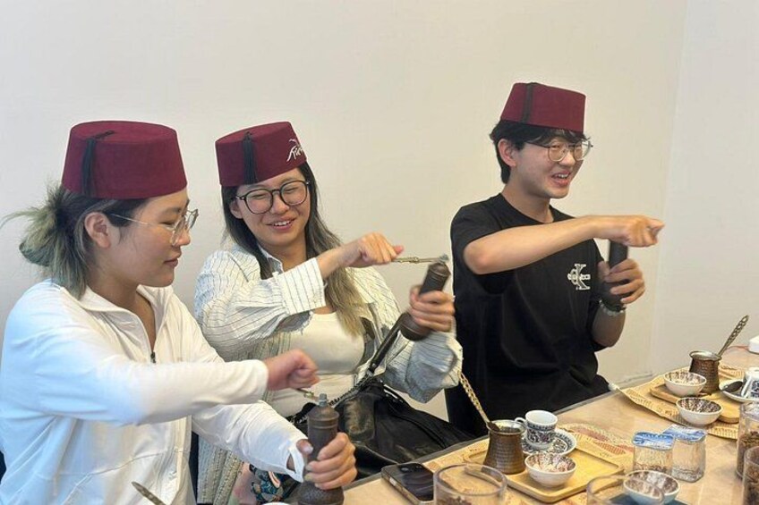Drie personen met hoeden, die een zwaard vasthouden en aan een tafel zitten met bekers en een dienblad. 3