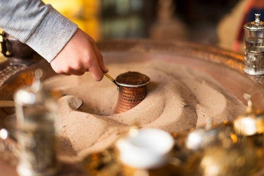Een hand roert iets in een metalen bakje op een dienblad. 1