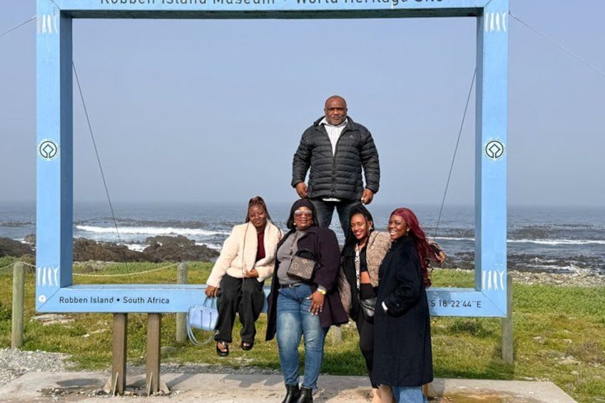 A group of people standing in front of a sign at Robben Island Museum in South Africa. 1