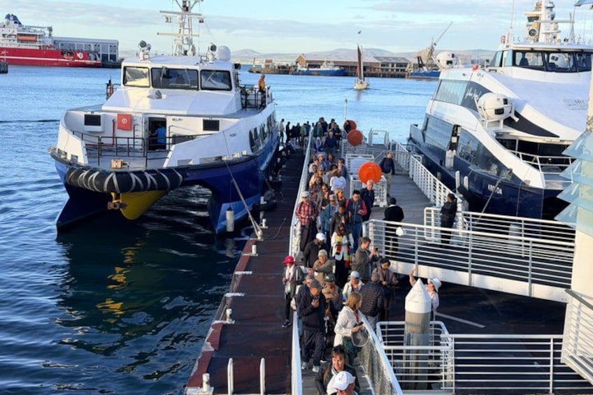 A ferry docked at a port with passengers boarding. 2