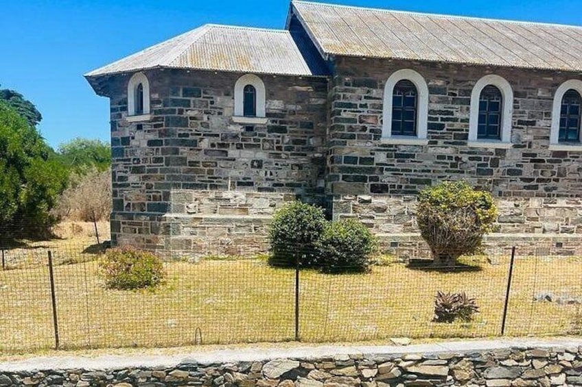 A stone building with a sloped roof and arched windows. 3