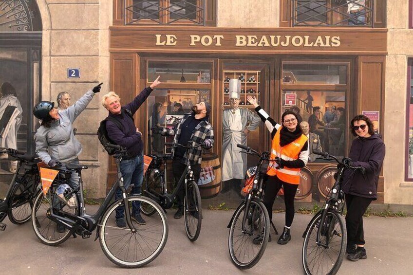 Un grupo de personas en bicicletas frente a un edificio con el letrero 'LE POT BEAUJOLAIS'. 5