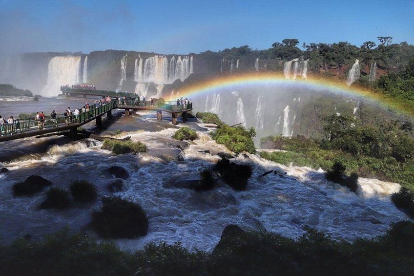 A waterfall with a rainbow, a viewing platform, and a bridge. 3