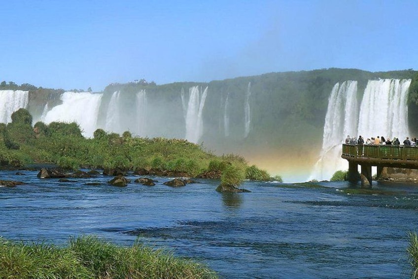 A large waterfall, a bridge with people, and a rainbow. 2