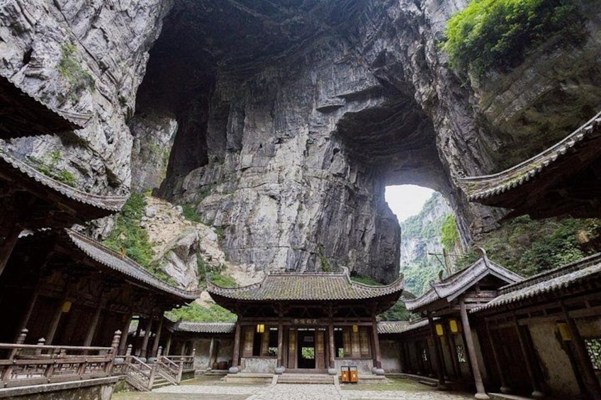 A traditional Chinese building with a large rock archway. 2