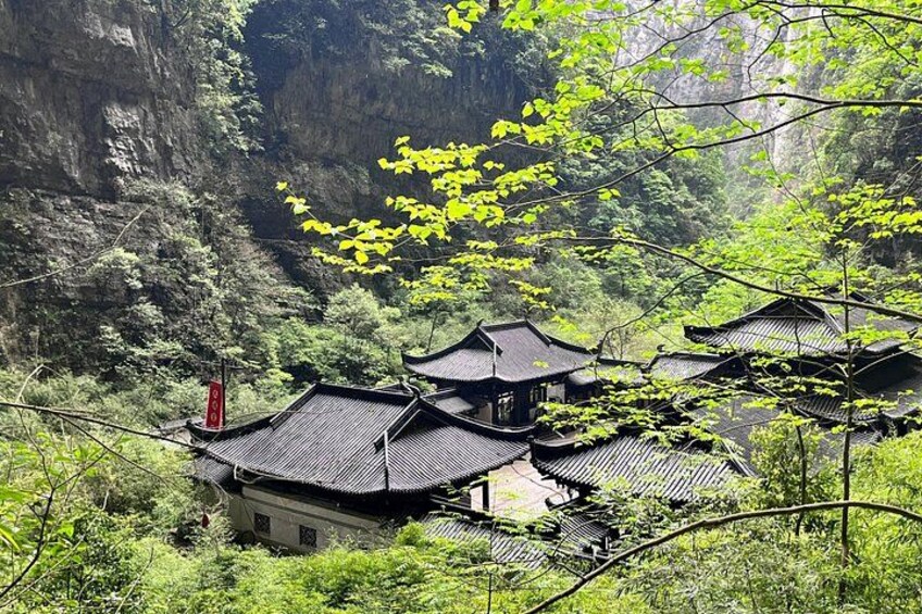 Traditional Chinese architecture nestled in a lush valley with steep cliffs. 1