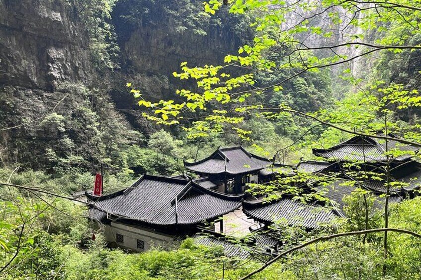 Traditional buildings nestled in a lush valley with steep cliffs. 1