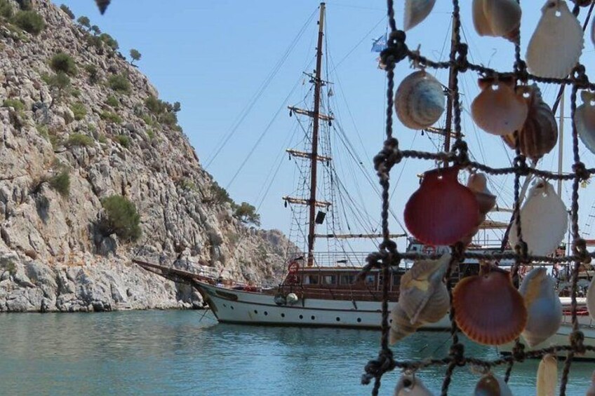 Una barca ormeggiata vicino a una costa rocciosa, con una rete piena di conchiglie in primo piano. 5