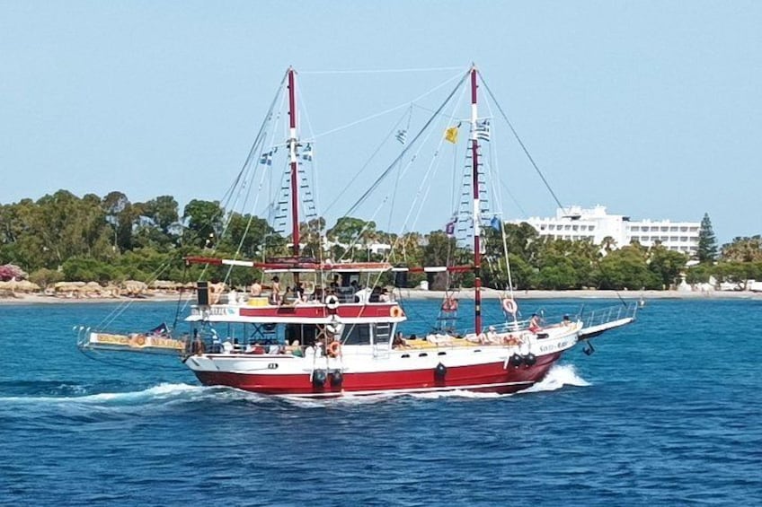 Una barca rosso e bianco con diversi alberi che naviga su acqua blu. 1