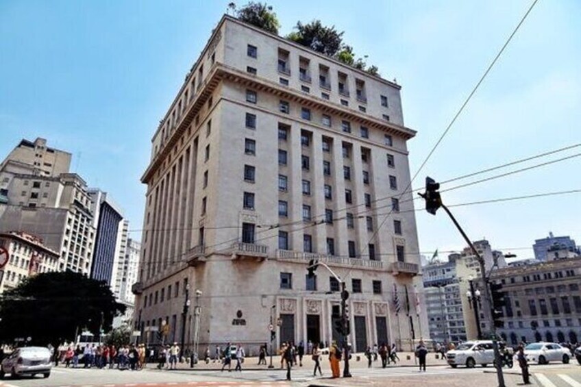 A large, historic building with a classical architectural style, surrounded by a busy urban street with pedestrians and vehicles. 1