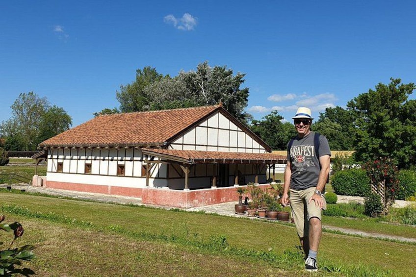 Een man staat voor een traditioneel huis met een pannendak en witte muren. 5
