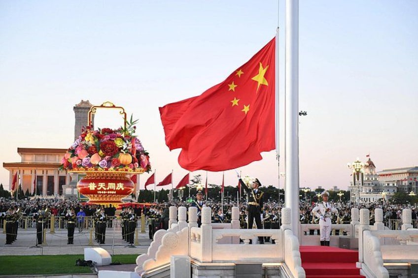 A ceremonial event with a large red flag, a floral arrangement, and a crowd of people. 1