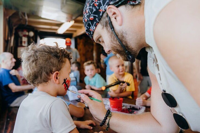 Una persona pintando a un niño con un pincel. 4