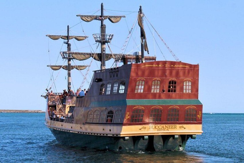 Un barco de vela alto llamado 'BUCCANEER', con varios mástiles y velas, atracado en el agua. 4