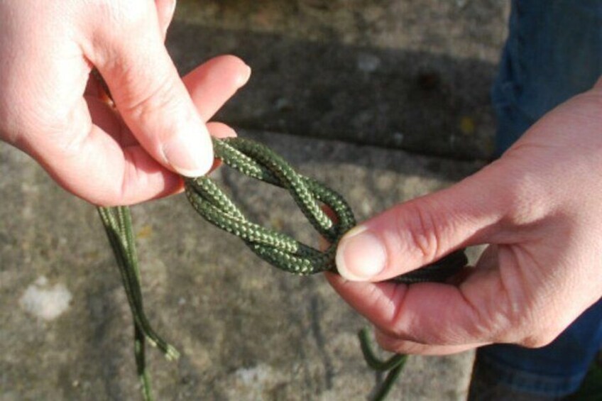 A person holding a green rope with a knot. 5