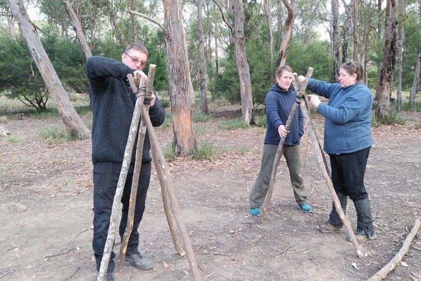 Three people assembling a tripod in a forest. 4