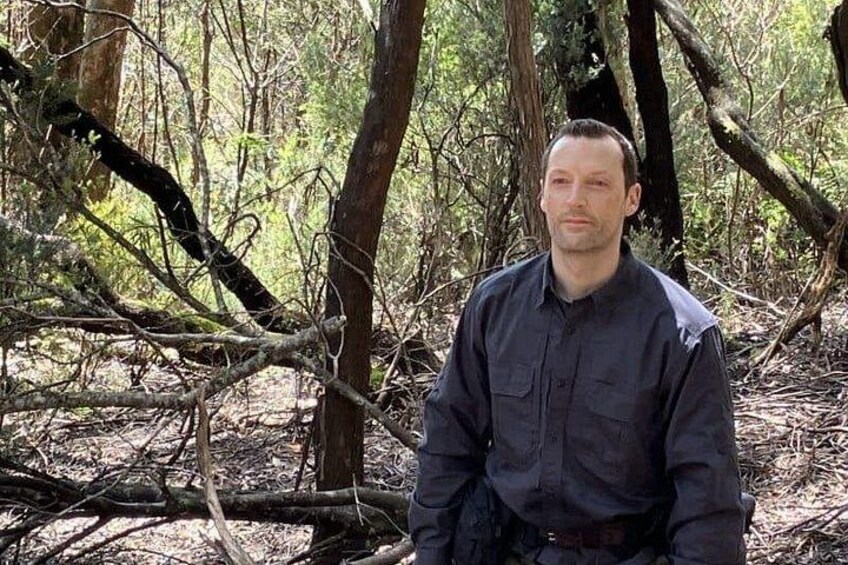 A person sitting in a forest with trees and branches around. 2