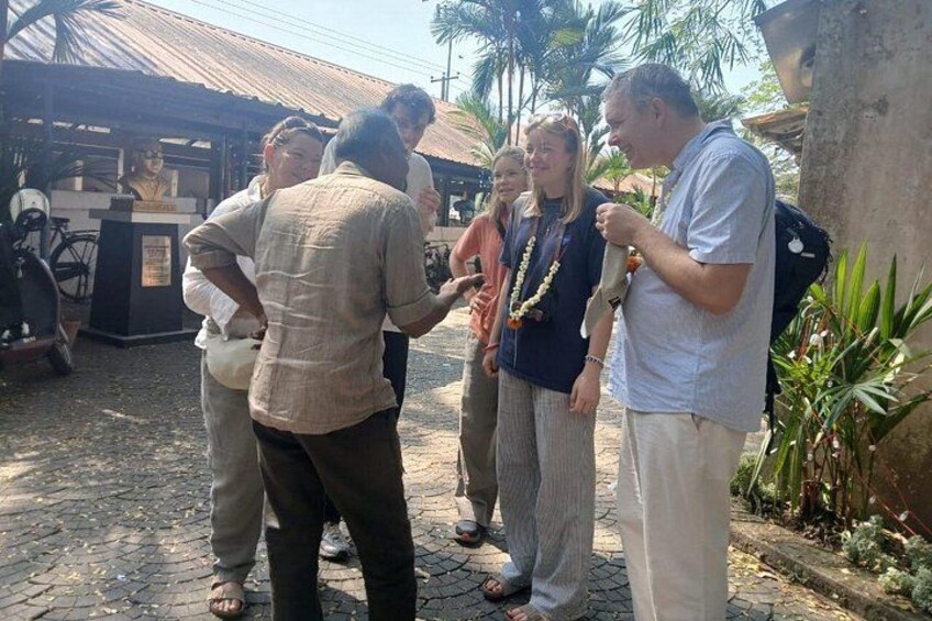 A group of people standing outdoors, some holding cameras, with a building and palm trees in the background. 3