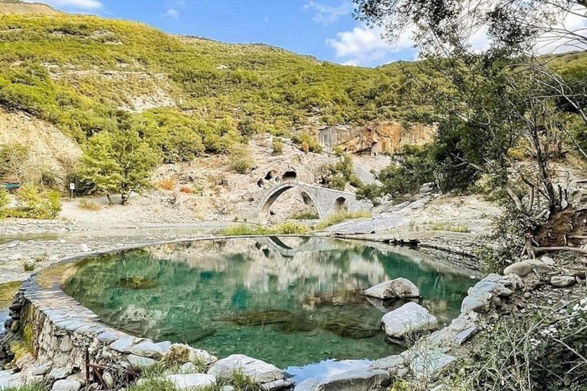 Un estanque de piedra circular con un puente al fondo. 5