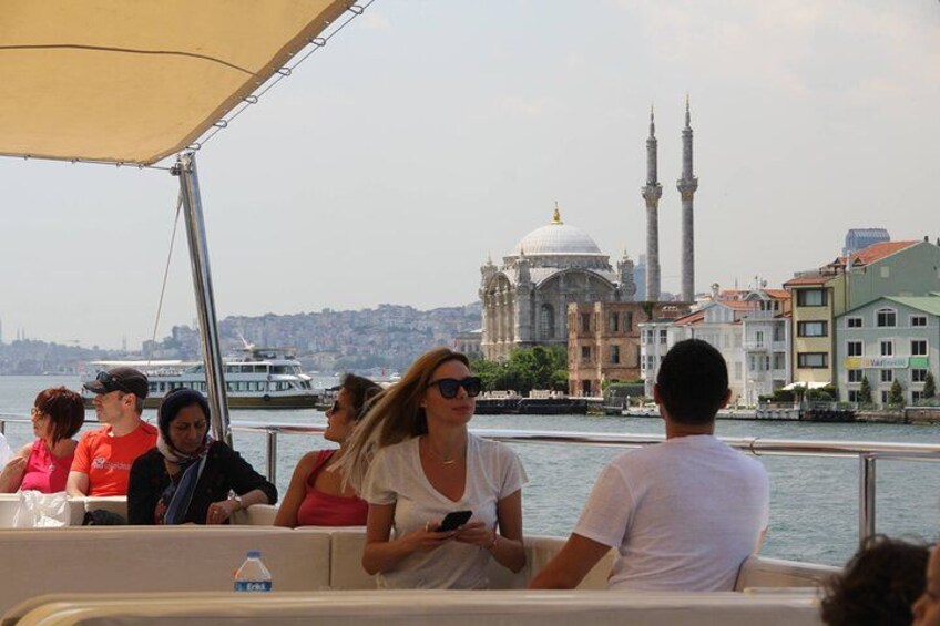 A boat with passengers, a mosque with two minarets, and a cityscape in the background. 2