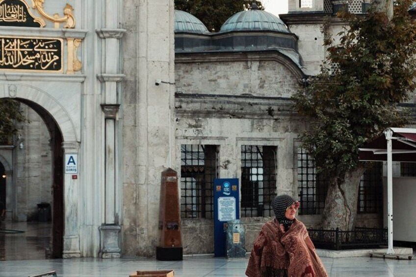 A historic building with an arched entrance, a dome, and a person in traditional attire standing in front. 3