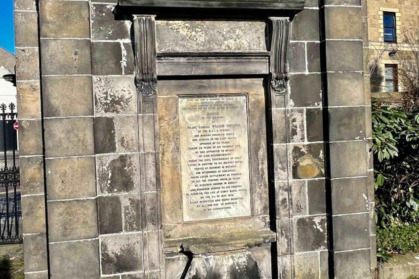 A stone monument with an inscription, set in a stone wall with decorative elements. 4
