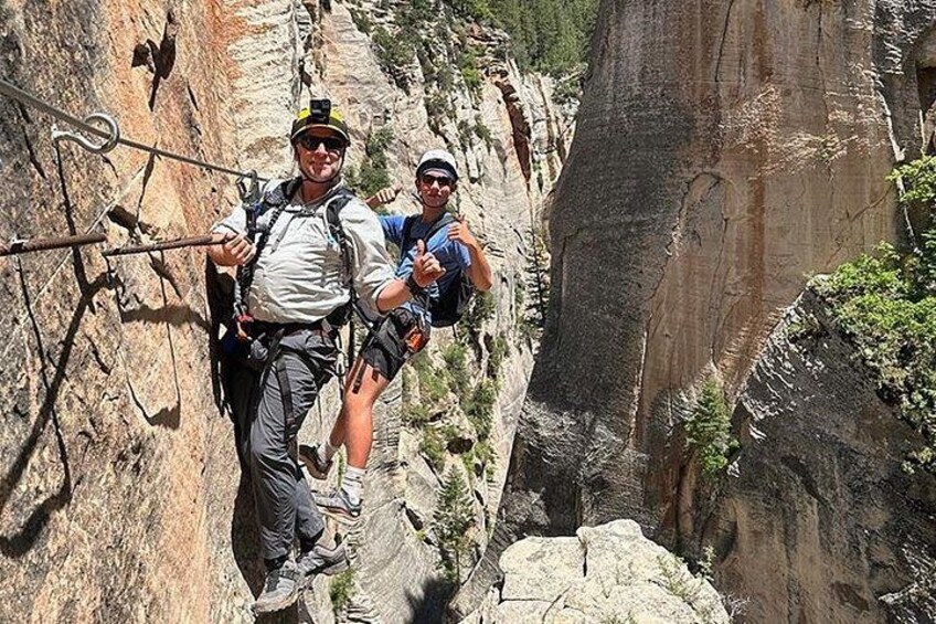 Two people climbing a rocky canyon with climbing gear. 3