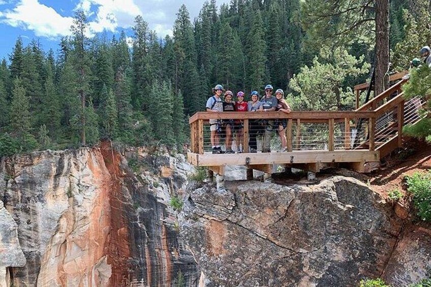 A wooden viewing platform with people overlooking a canyon with red rock formations. 2