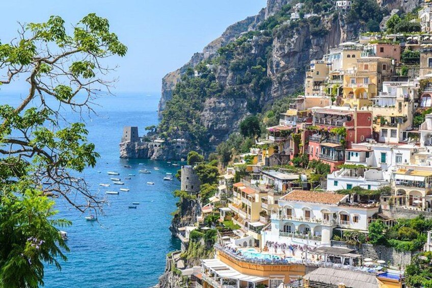 Une ville côtière aux bâtiments colorés, avec une falaise rocheuse et des bateaux sur l’eau. 2