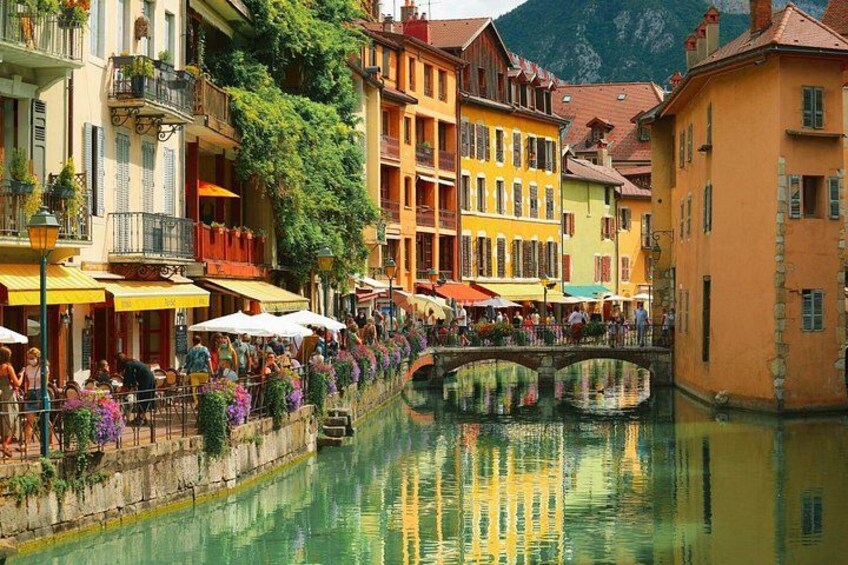 Un canal bordé de bâtiments aux couleurs vives, un pont et des gens profitant des terrasses des cafés. 3