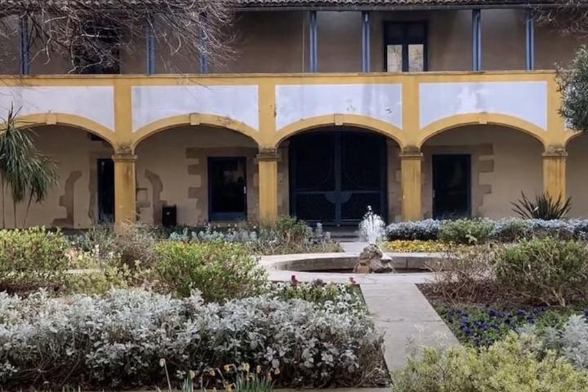 A building with a yellow facade, arched doorways, and a central fountain. 2
